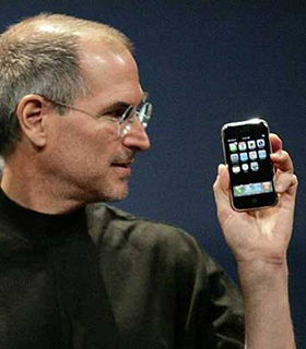 Steve Jobs hält das erste iPhone in der Hand.